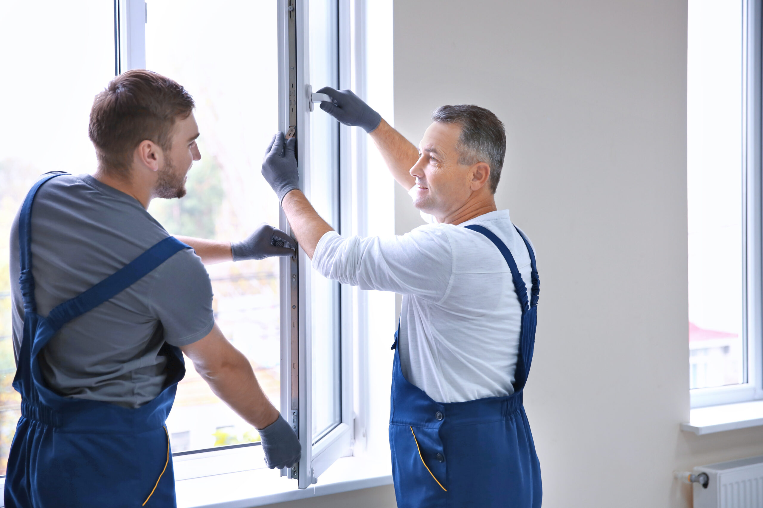 Construction worker with trainee installing window in house