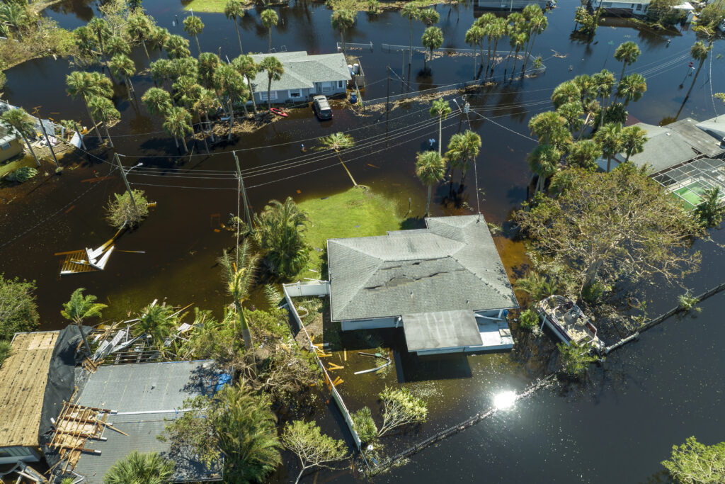 A flooded residential area with damaged roofs and submerged yards, emphasizing the importance of home preparation for hurricane season.