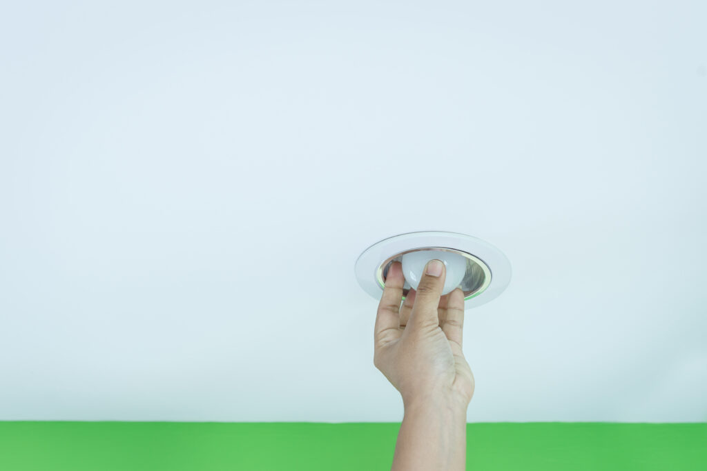 Close up hand holding light bulb on the ceiling